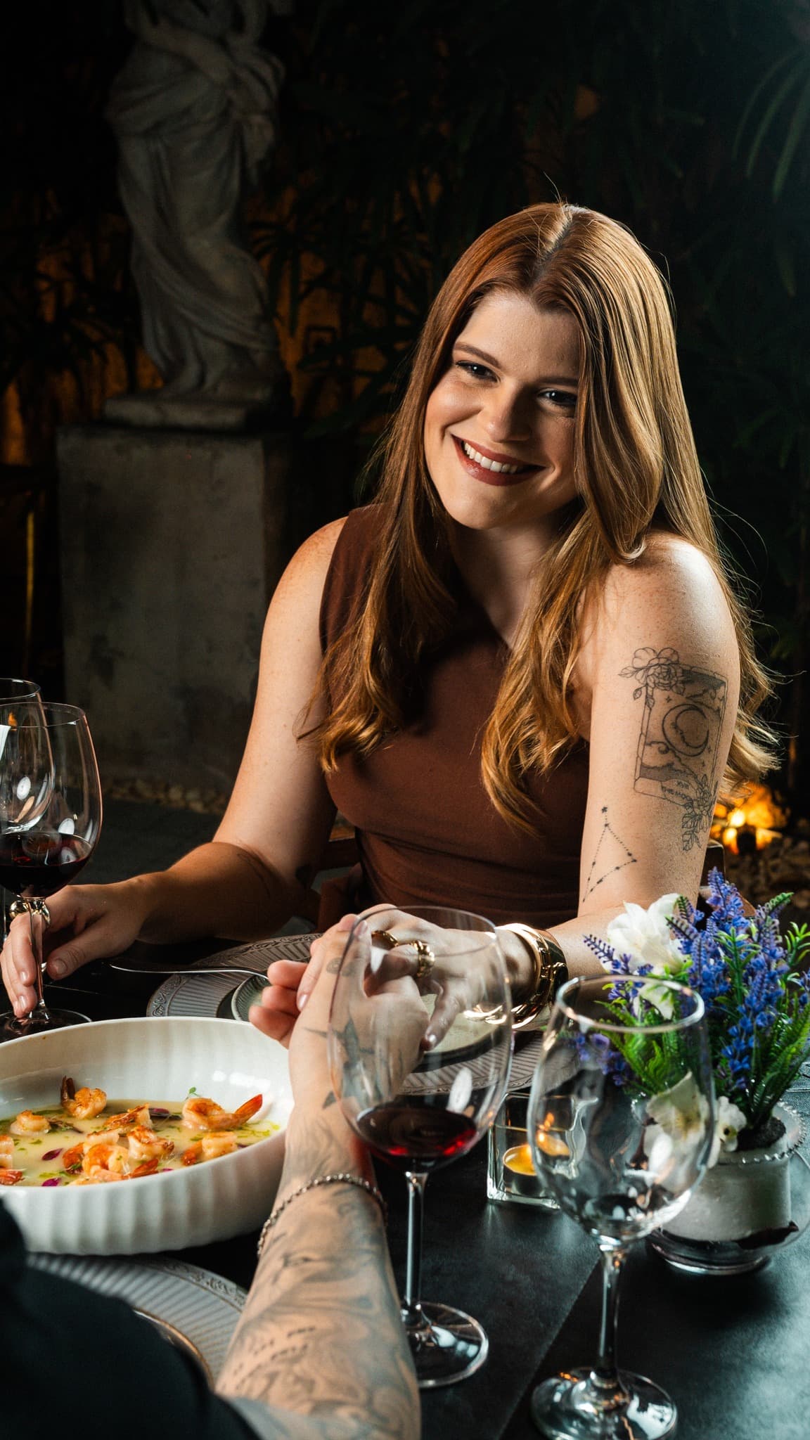 Casal brindando à mesa do Çavá, com camarões e vinho tinto