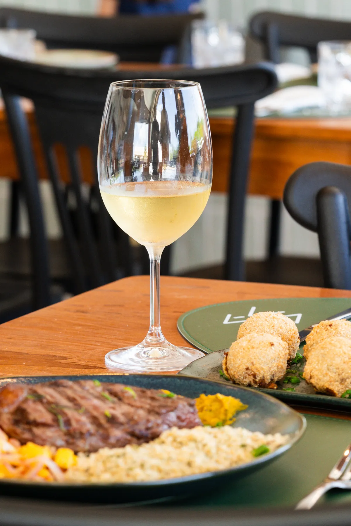 Taça de vinho branco na mesa do Ça-Vá Santo Amaro, ao lado dos pratos
